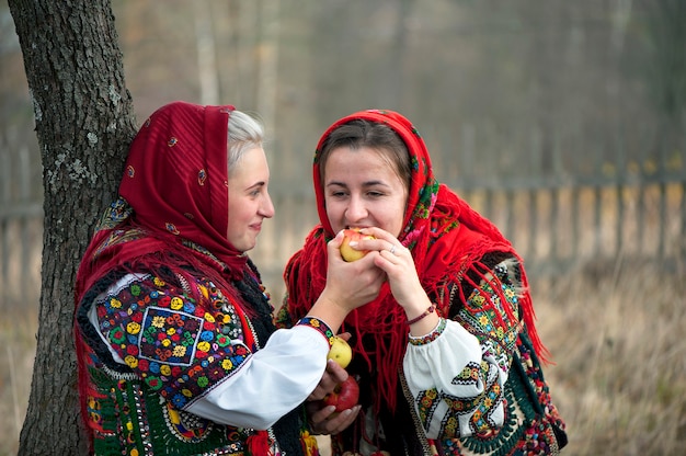 Le ragazze vestite con antichi e pittoreschi abiti nazionali Hutsul mangiano una mela. Ucraina.