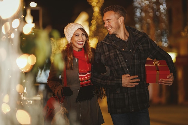 Le riprese di una giovane coppia allegra si divertono nella strada della città la notte di Natale. Stanno ridendo e comprano regali per le vacanze a venire.