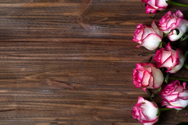 Le rose incorniciano su fondo marrone di legno