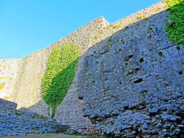 Le rovine di un'antica fortezza vecchi spessi muri di pietra di una fortezza europea ricoperta di vegetazione in montagna Porte e archi tra le rovine delle fortificazioni