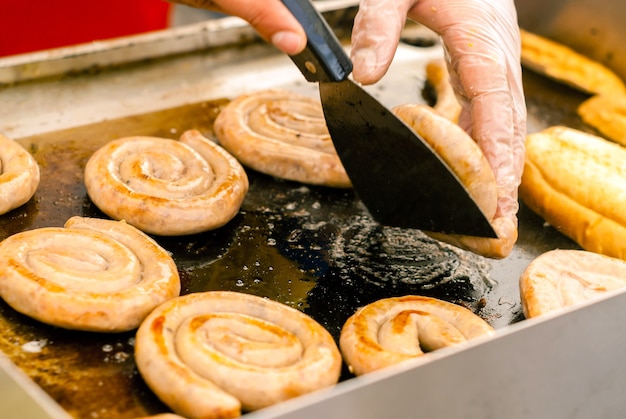 Le salsicce a spirale sono fritte nel burro su una teglia da forno in un caffè di strada da vicino