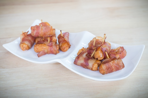 Le salsicce fritte in profondità hanno rotolato in pancetta affumicata