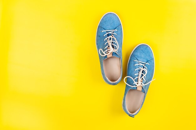 Le scarpe blu stanno su uno sfondo giallo isolato.