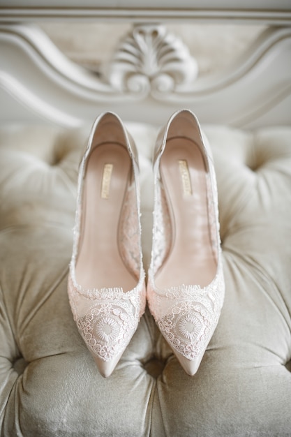 Le scarpe della sposa con i lacci stanno sul sofà bianco