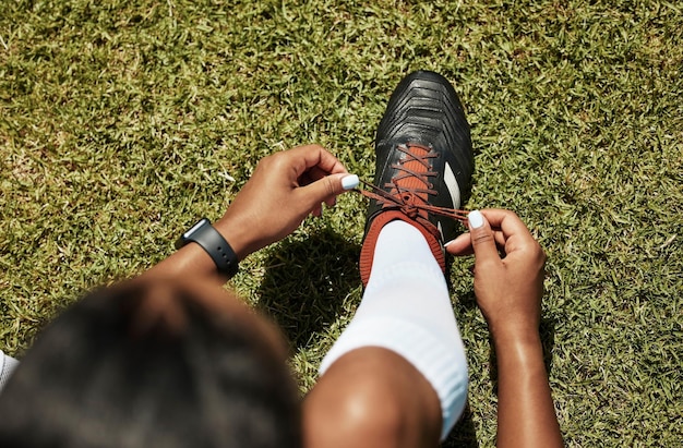 Le scarpe legano sport e calcio atleta donna nera su erba verde pronto per l'esercizio e l'allenamento Allenamento fitness e gioco di un giocatore di persona sana prima del cardio di calcio in natura e in estate
