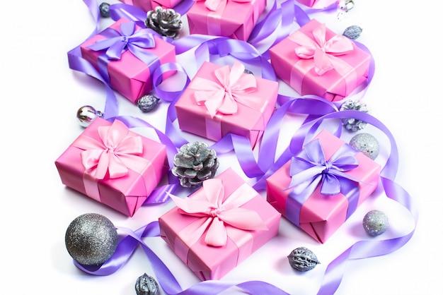 Le scatole di Natale con i regali in occasione di colore rosa sulla decorazione bianca dei coni dei coni di fondo