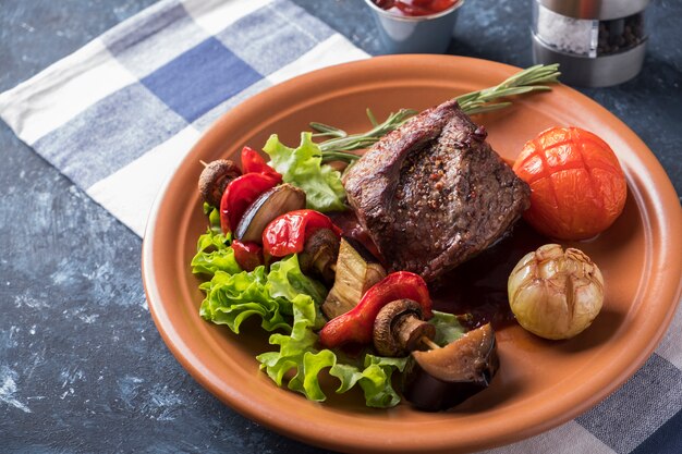 Le spezie della bistecca di manzo hanno servito le verdure arrosto su un piatto.