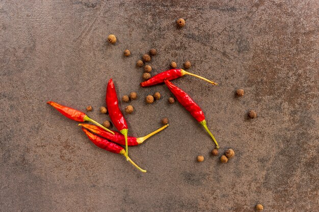 Le spezie di pepe nero e peperoncino giacciono su un tagliere di pietra scura