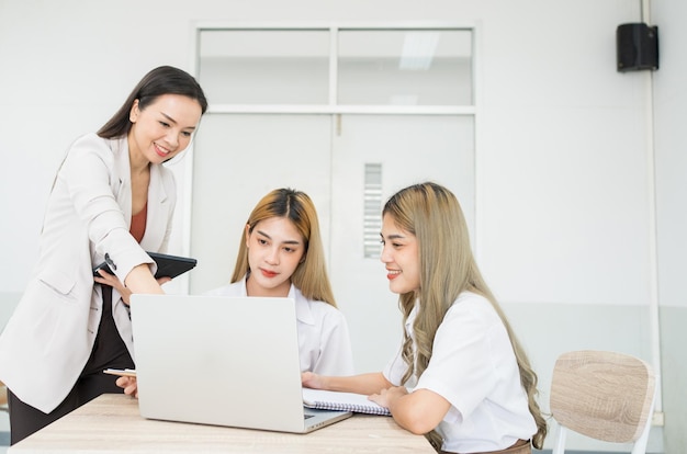 Le studentesse asiatiche di gruppo dell'università spiegano e presentano con la professoressa insegnante in classe