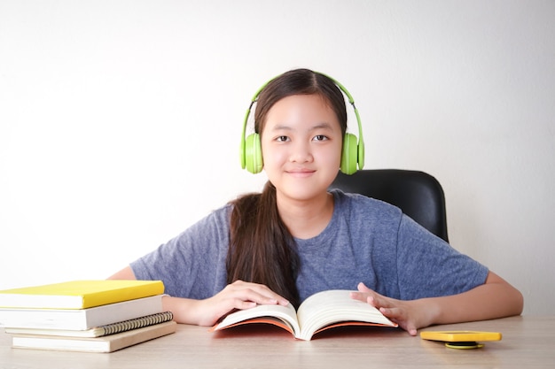 Le studentesse asiatiche imparano online da casa. Metti le cuffie e leggi un libro. Concetto di distanza sociale Uso della tecnologia per l'istruzione.