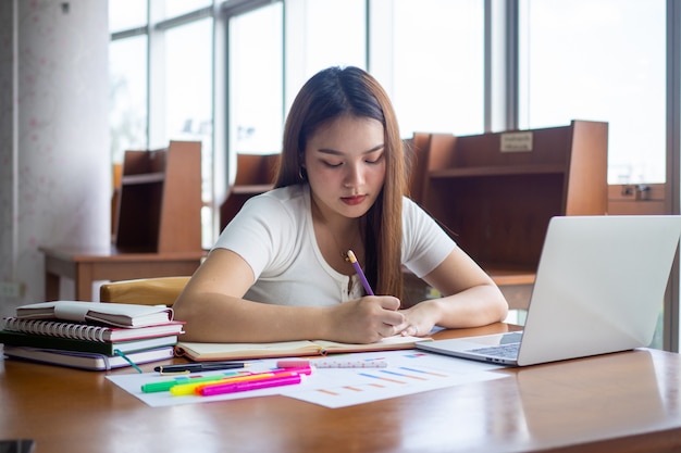 Le studentesse si siedono e fanno i compiti Prendere appunti, fare relazioni in biblioteca.