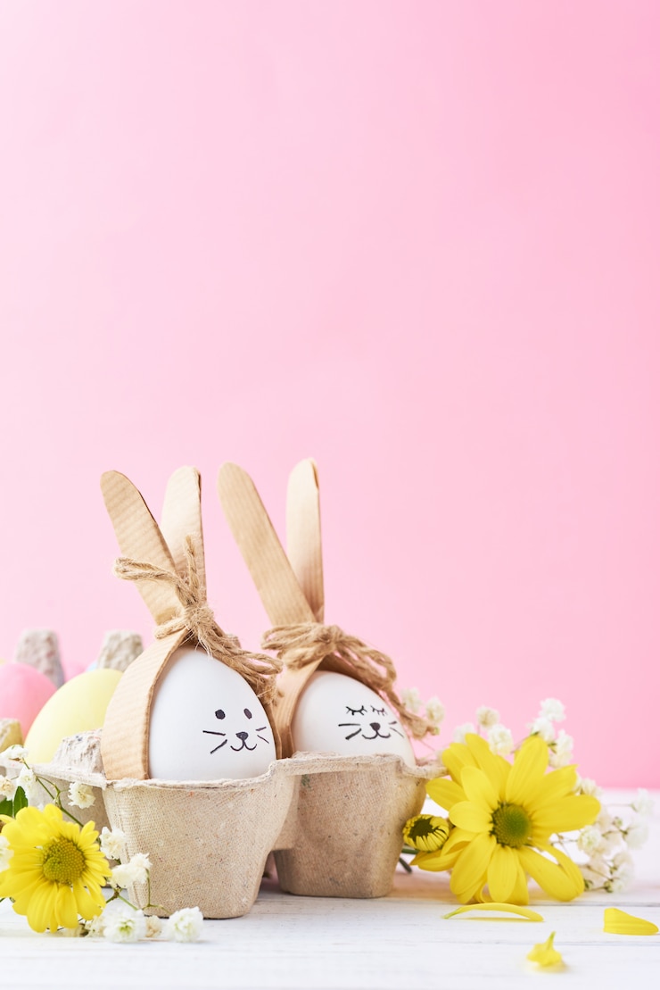 Le uova colorate Pasqua con i fronti dipinti in vassoio con decorationd su un rosa