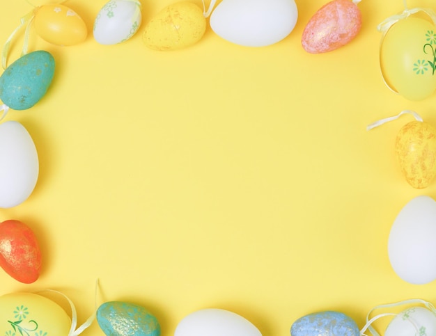 Le uova di Pasqua decorative sono disposte in una cornice quadrata su sfondo giallo