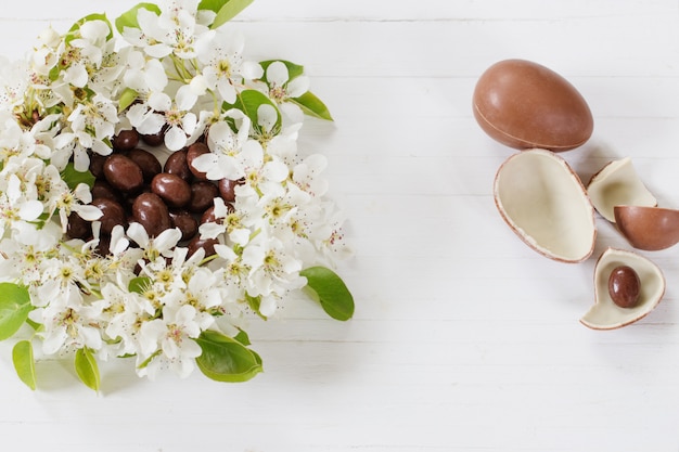 Le uova di Pasqua del cioccolato con la molla fiorisce su fondo di legno