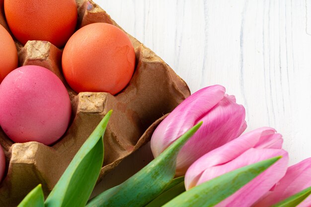 Le uova di Pasqua dipinte in un eggbox con i tulipani freschi si chiudono su