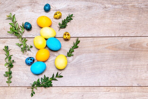 le uova di pasqua giacciono nel secchio giallo arredamento su fondo di legno con la molla dei rami della pianta verde