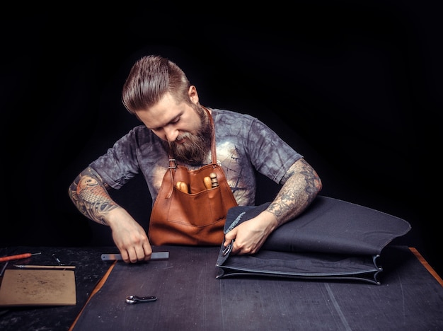 Leather Craftsman concentrandosi sul suo lavoro nel suo studio di pelletteria