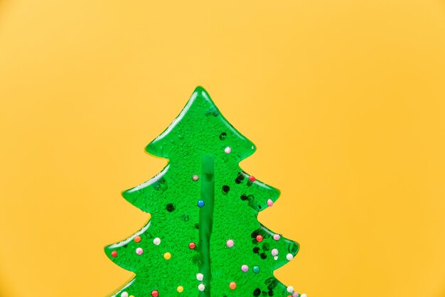 Lecca-lecca a forma di albero di Natale di close-up su un giallo.