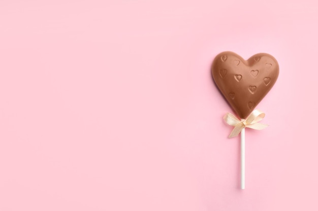 Lecca-lecca a forma di cuore al cioccolato su sfondo rosa chiaro vista dall'alto Spazio per il testo