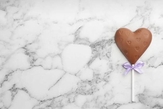 Lecca-lecca a forma di cuore al cioccolato su vista dall'alto del tavolo in marmo bianco Spazio per il testo