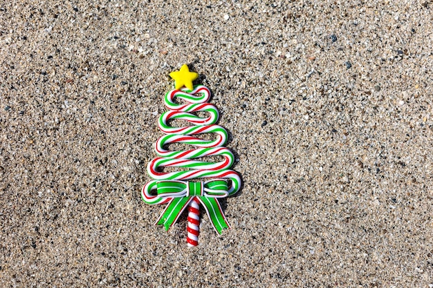Lecca-lecca dell'albero di Natale sullo sfondo di Natale della sabbia con lo spazio della copia per testo