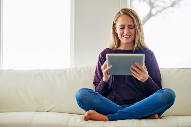 Leggere online e donna con tablet lounge e sorriso per l'amore ebook per break chill e casa soggiorno rilassarsi e ragazza sul divano digitale e intrattenimento di finzione con internet in app