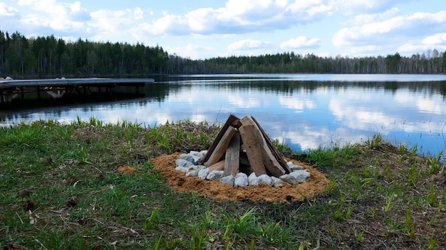 Legna da ardere impilata a forma di capanna per accendere un fuoco sulla riva di un lago nella foresta