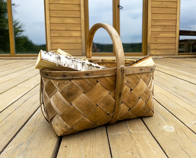 Legna da ardere in un cesto di vigneti su una terrazza in legno