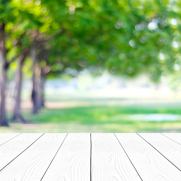 Legno bianco di prospettiva sopra gli alberi della sfuocatura con il fondo del bokeh