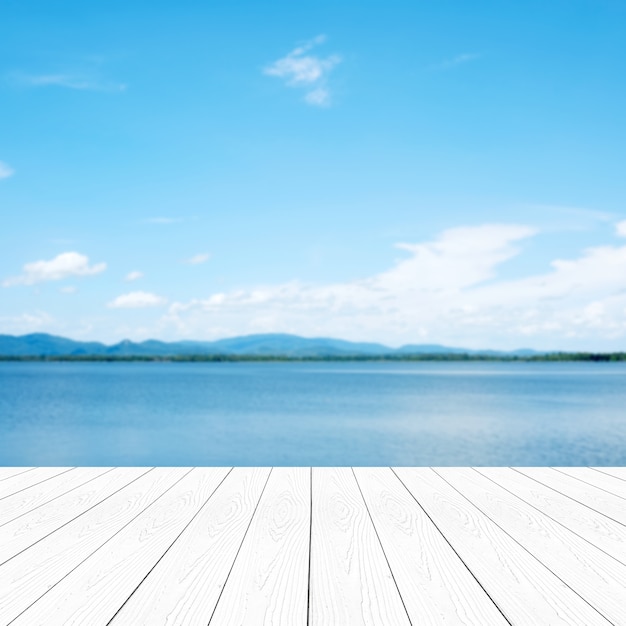 Legno bianco di prospettiva vuota sopra il fondo blu del mare e del cielo della sfuocatura