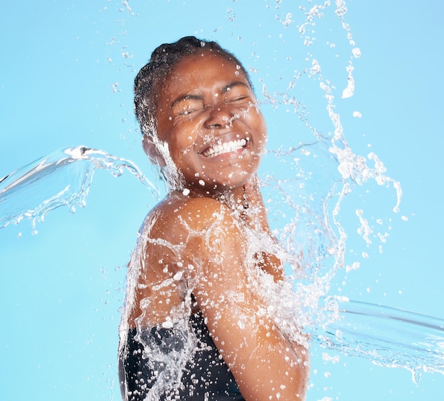 Lei sa come divertirsi. Inquadratura di una giovane e bella donna spruzzata d'acqua su uno sfondo blu.