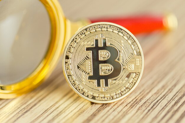 Lente d&#39;ingrandimento con moneta d&#39;oro bitcoin