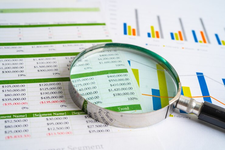 Foto lente di ingrandimento su grafici carta millimetrata sviluppo finanziario conto bancario