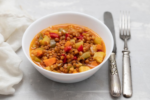 Lenticchie con zucchine peperoni e cipolla su piatto bianco