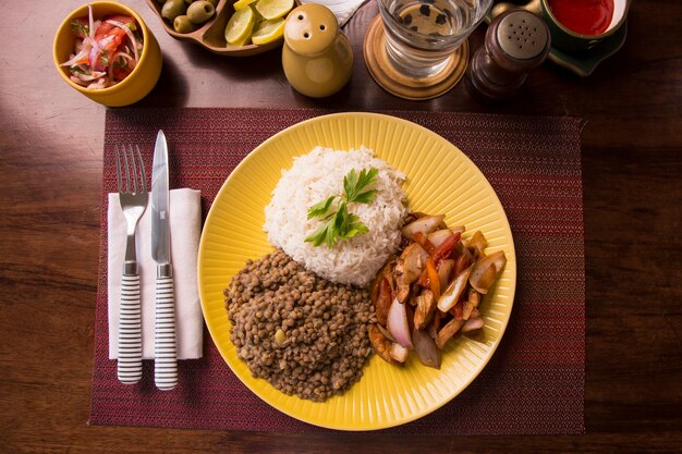 Lenticchie saltate pollo riso peruviano cibo tradizionale mise en place tavola di legno