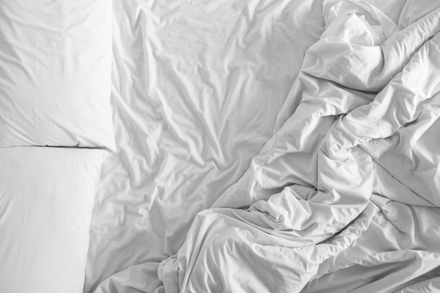 Lenzuola e cuscini sconvolti dopo notti di sonno, comfort e biancheria da letto in una camera d&#39;albergo, viaggio di concetto e di vacanza