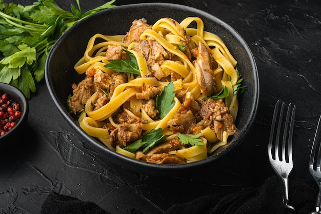 Lepre selvatica con verdure in salsa di vino bianco tagliatelle di pasta o pappardelle set, nella ciotola, sul tavolo di pietra nera