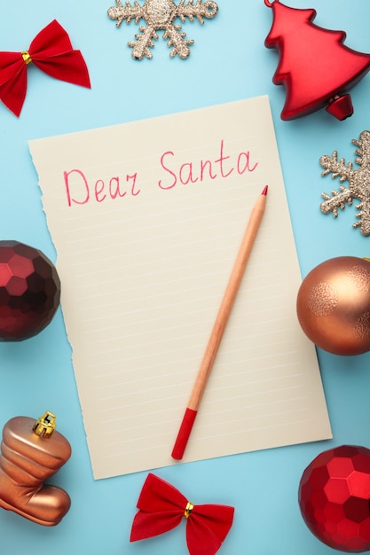 Lettera a Babbo Natale con decorazioni natalizie su sfondo blu. Iscrizione Caro Babbo Natale. Foto verticale