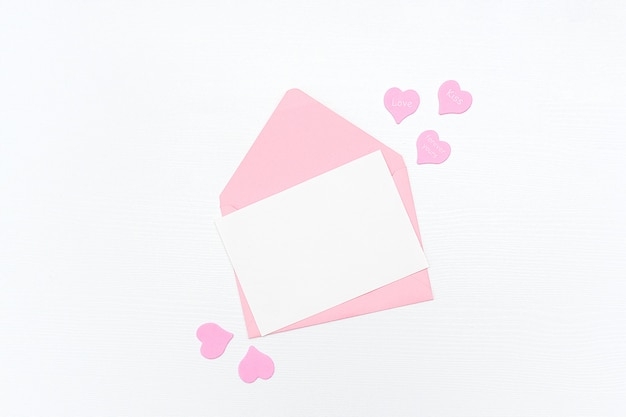 Lettera d'amore. Busta rosa con la carta in bianco bianca e cuori su bianco