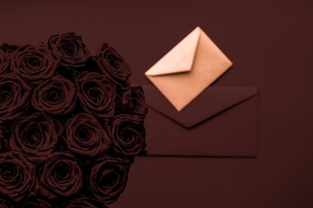 Lettera d'amore e consegna di fiori il giorno di San Valentino lussuoso bouquet di rose e carta su sfondo di cioccolato per un design romantico per le vacanze