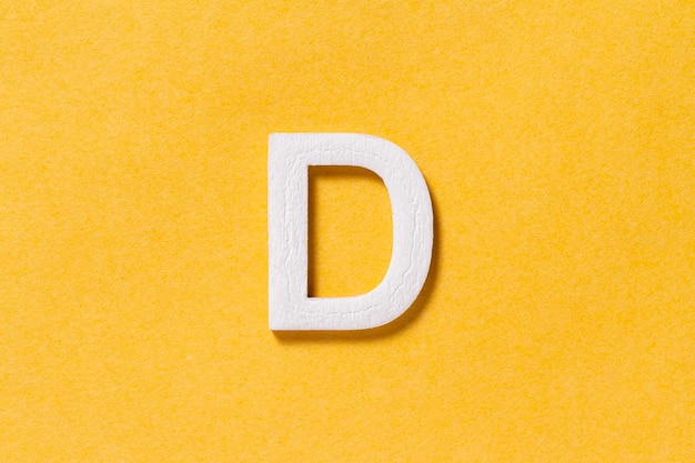 Lettera D dell'alfabeto isolata su sfondo giallo vista dall'alto