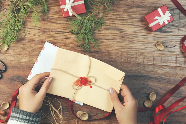 Lettera della mano della donna con gli oggetti di cristmas sulla tavola