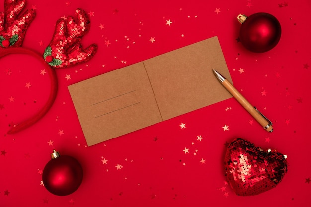 Lettera di Natale per congratulazioni con penna e decorazioni sulla superficie rossa.