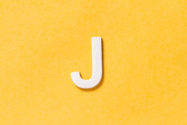 Lettera J dell'alfabeto isolata su sfondo giallo vista dall'alto