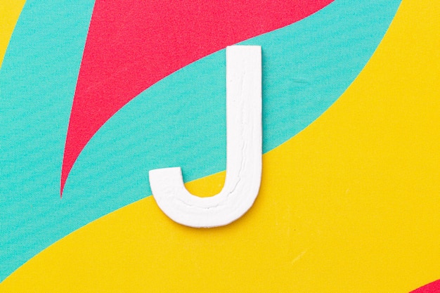 Lettera J dell'alfabeto su sfondo colorato vista dall'alto
