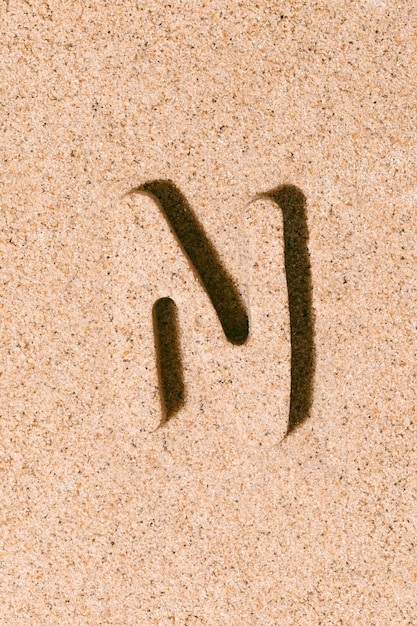 Lettera N della sabbia isolata sul concetto di sabbia della spiaggia dell'alfabeto estivo