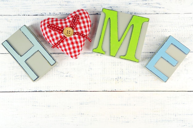Lettere decorative che formano la parola CASA con cuore decorativo su sfondo di legno