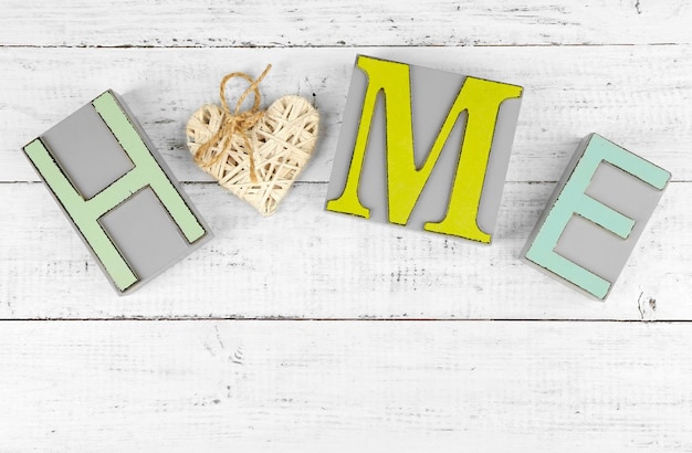 Lettere decorative che formano la parola CASA con cuore decorativo su sfondo di legno