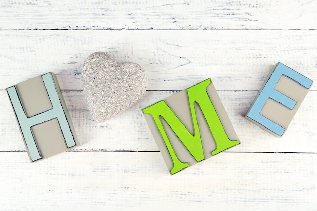 Lettere decorative che formano la parola HOME con cuore decorativo su sfondo di legno