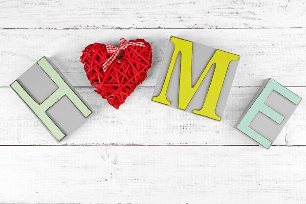 Lettere decorative che formano la parola HOME con cuore decorativo su sfondo di legno